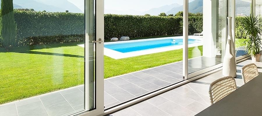 Grande porte-fenêtre et baie coulissante blanche avec vue sur piscine