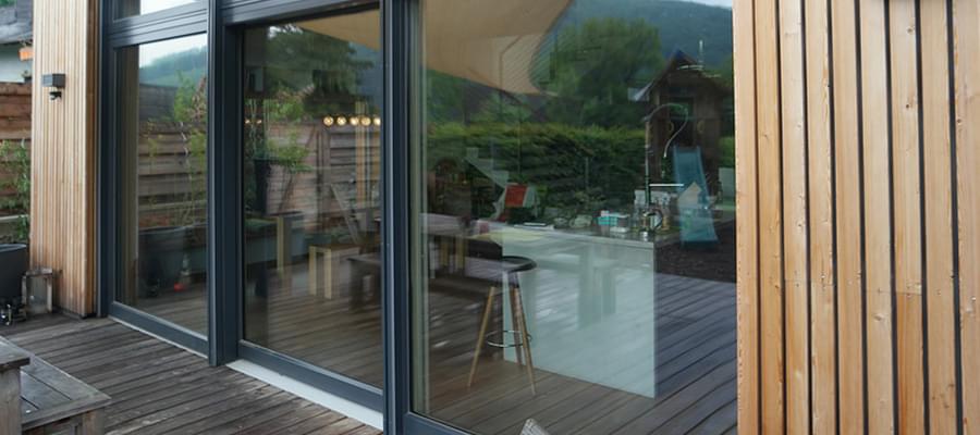 Porte extérieure coulissante grise dans construction en bois